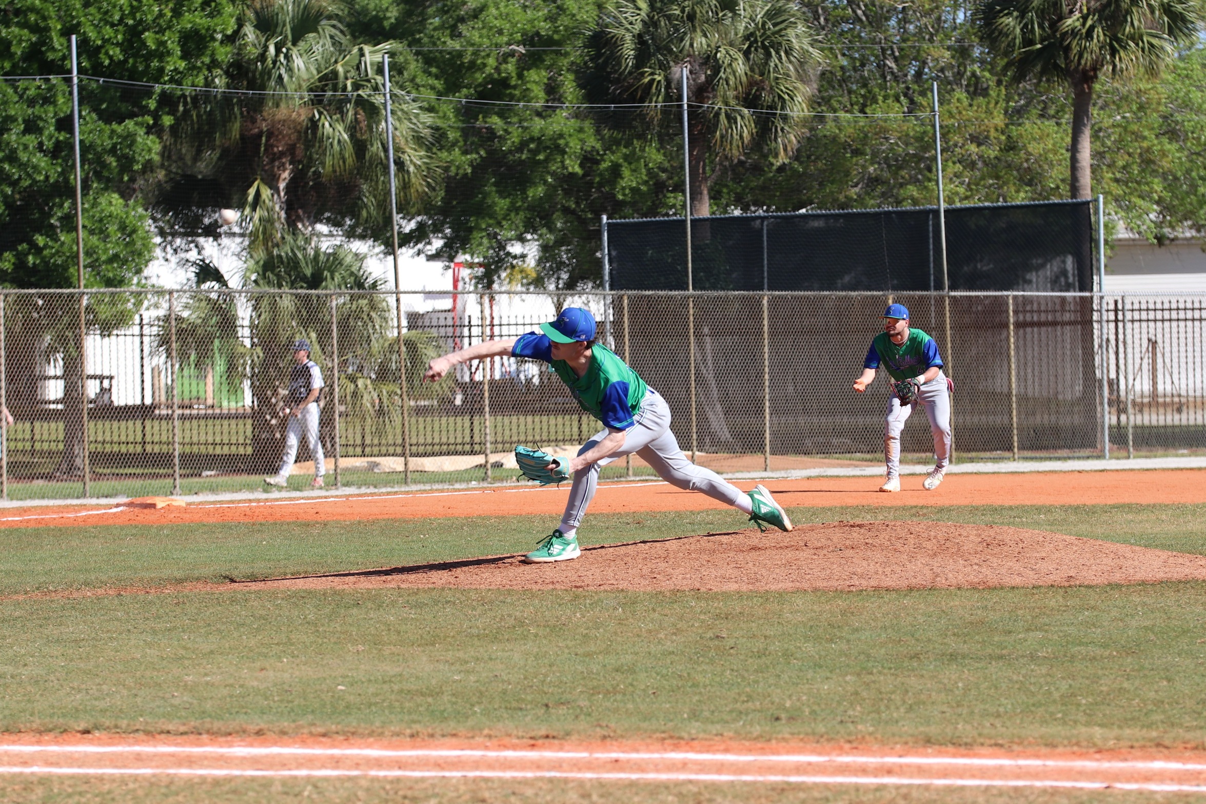 Cohen Thompson releases a pitch as the third baseman gets ready in the background