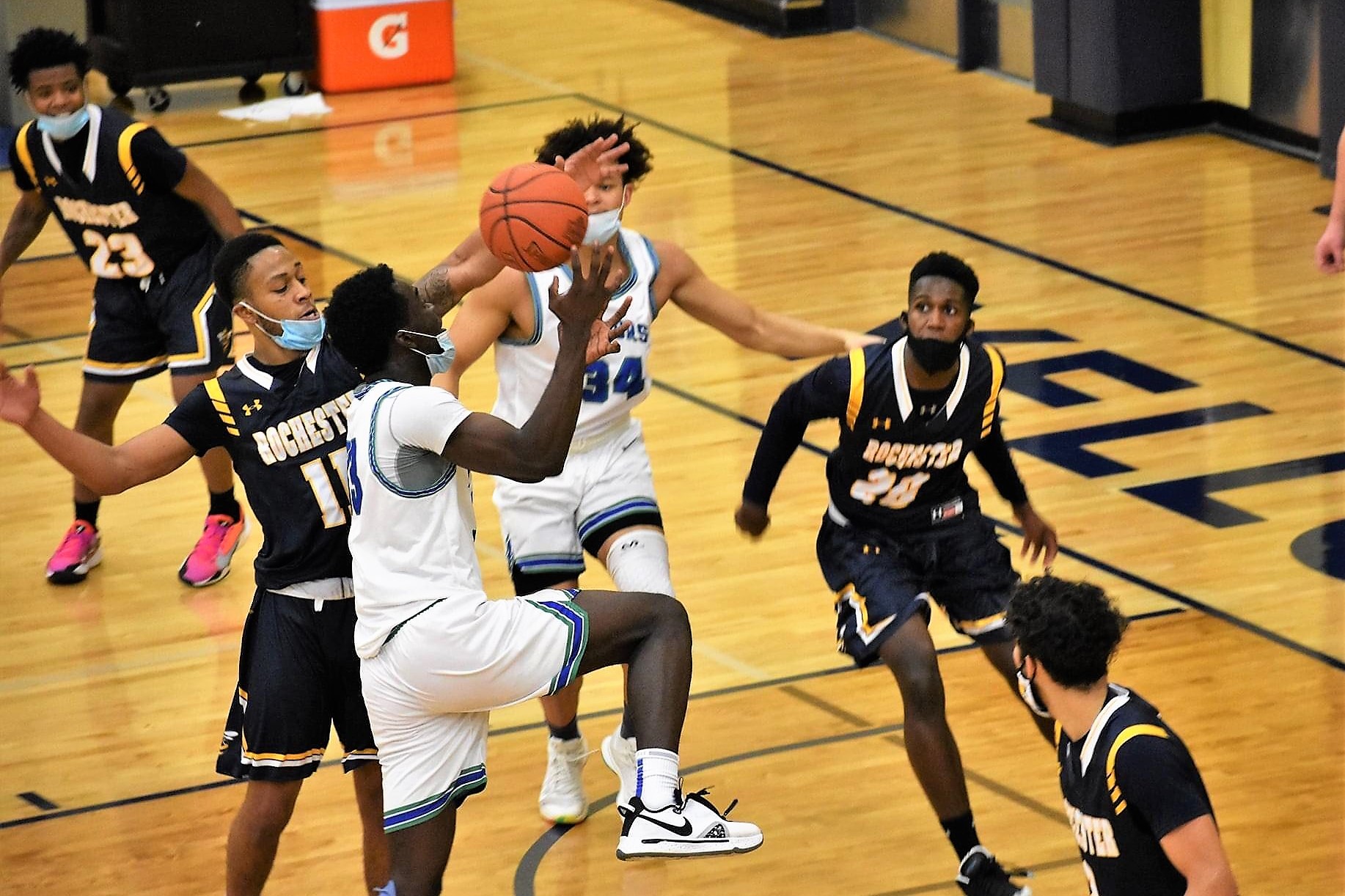 Didier Ngambo going up for a shot at the rim surrounded by defenders