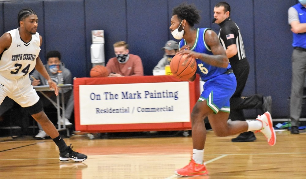 Savion Gray dribbling the ball up the court as a defender looks on