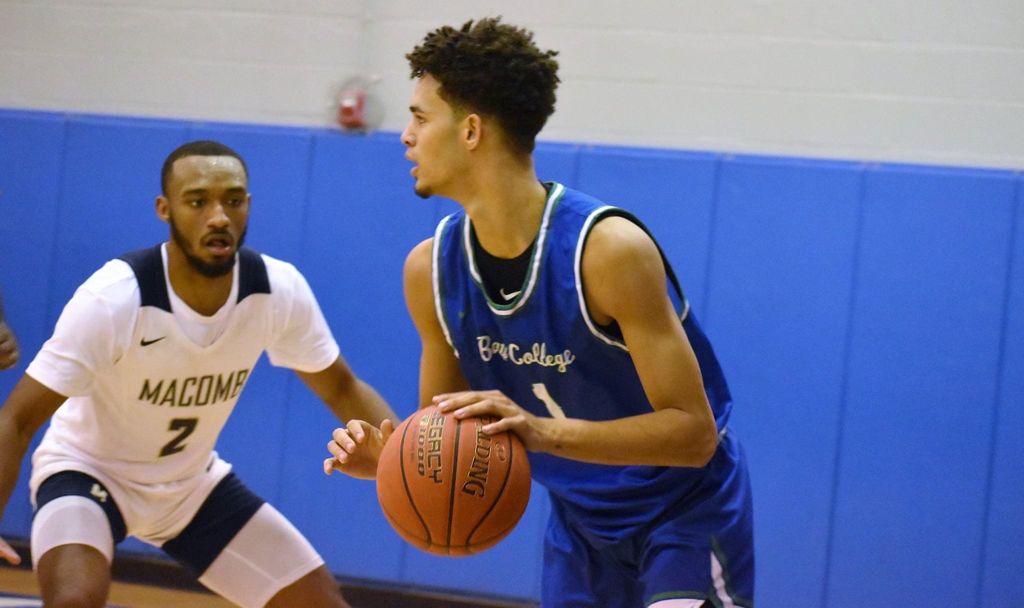 Jacquez Overstreet looks over the flor as he dibbles to his left, a defender looks on.