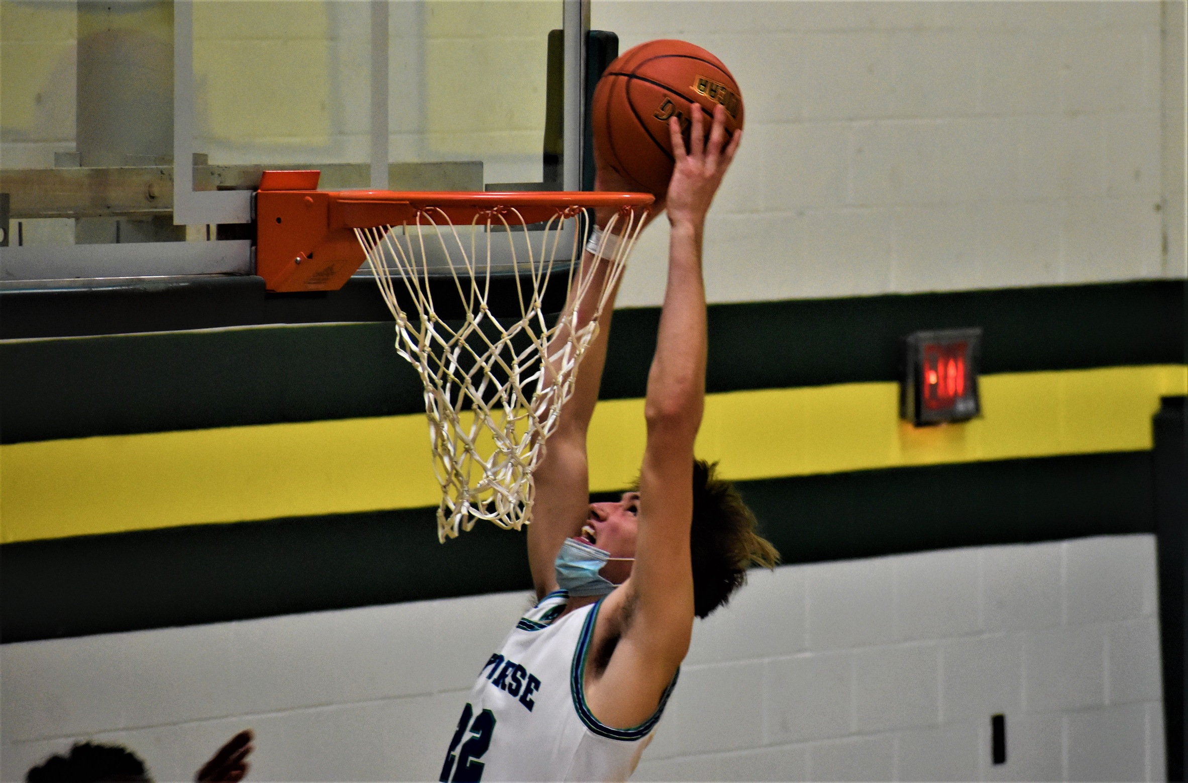 Justin Nelson with the ball above the rim, about to dunk it
