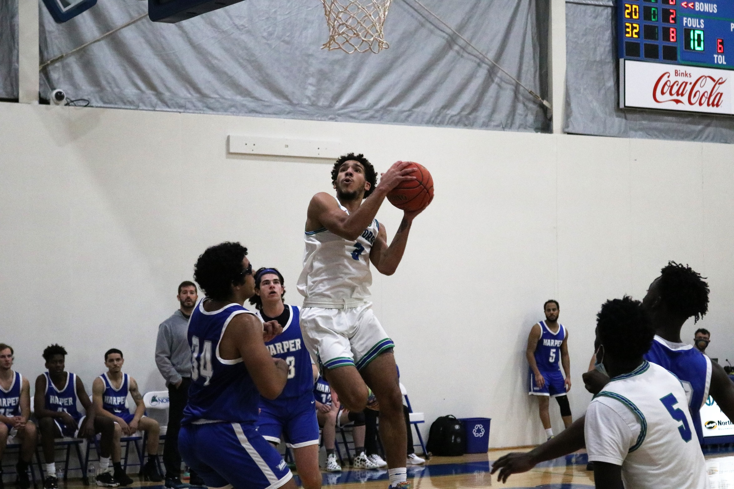 Tre Burris in mid air in the land avoiding the defense and about to put up a shot