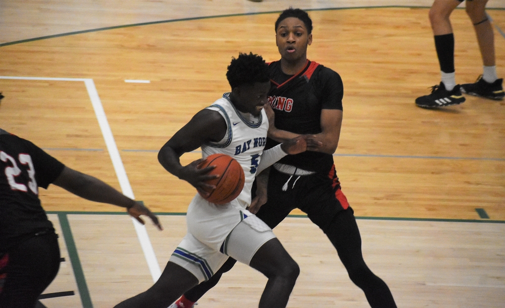 Jaylen Flaniken dirbbling through the lane with a defender in contact on his side