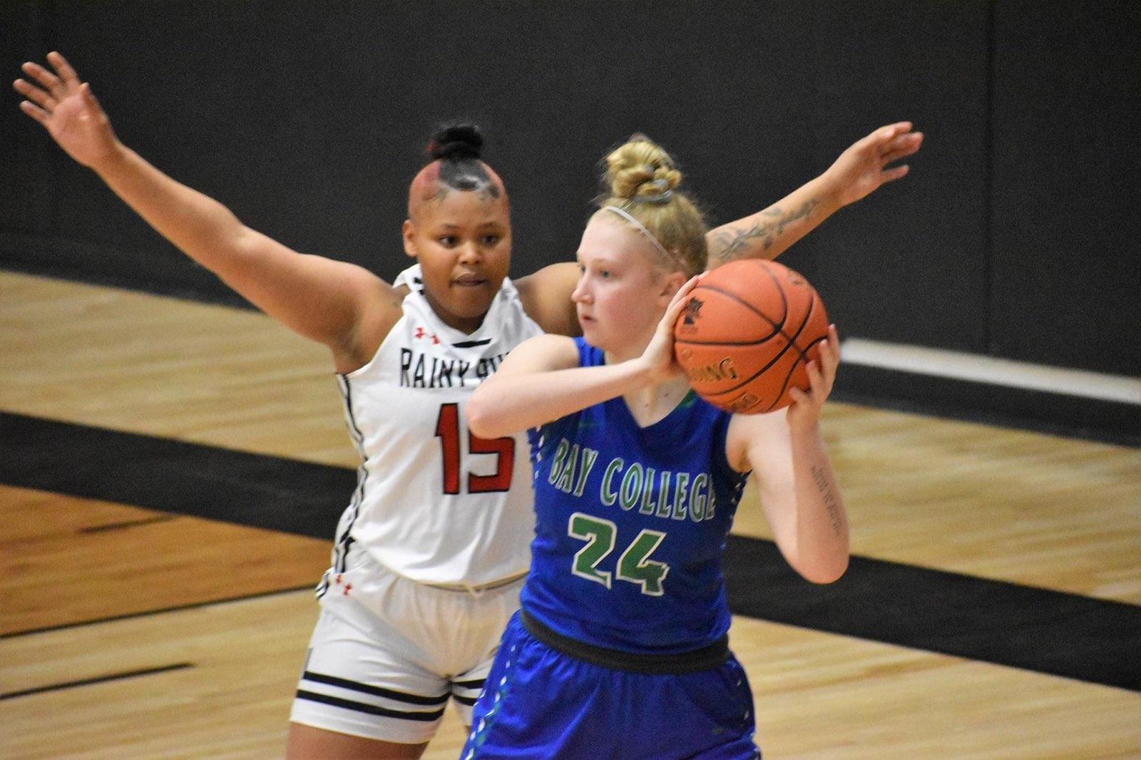 Madison Olsen holds the ball with a defender with her arms outstretched on her back